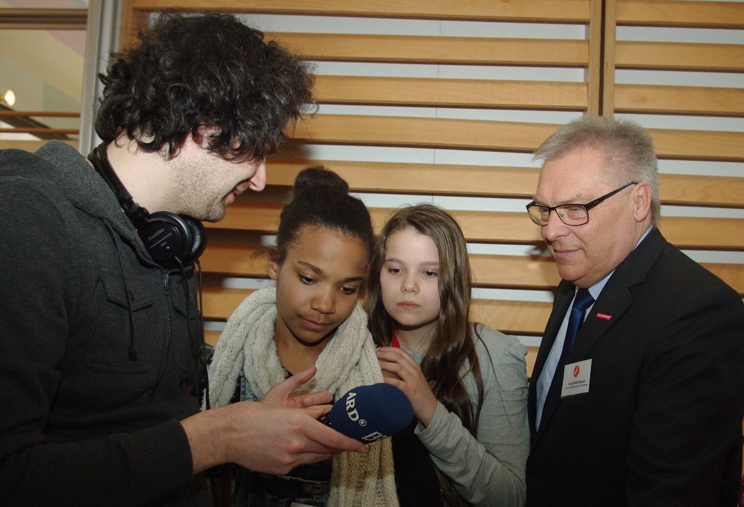 Während Mischa Drautz vom Bayerischen Rundfunk Joana Henzold und Dilara Kavak den Umgang mit dem Mikro erklärt, blickt HWK-Präsident Hans-Peter Rauch interessiert über die Schulter.